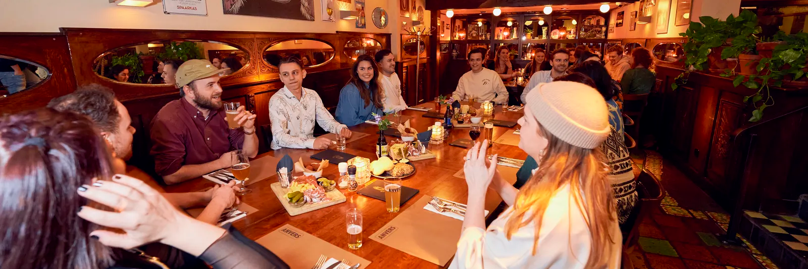 Gasten van Anvers nuttigen een drankje en versnaperingen in het restaurant