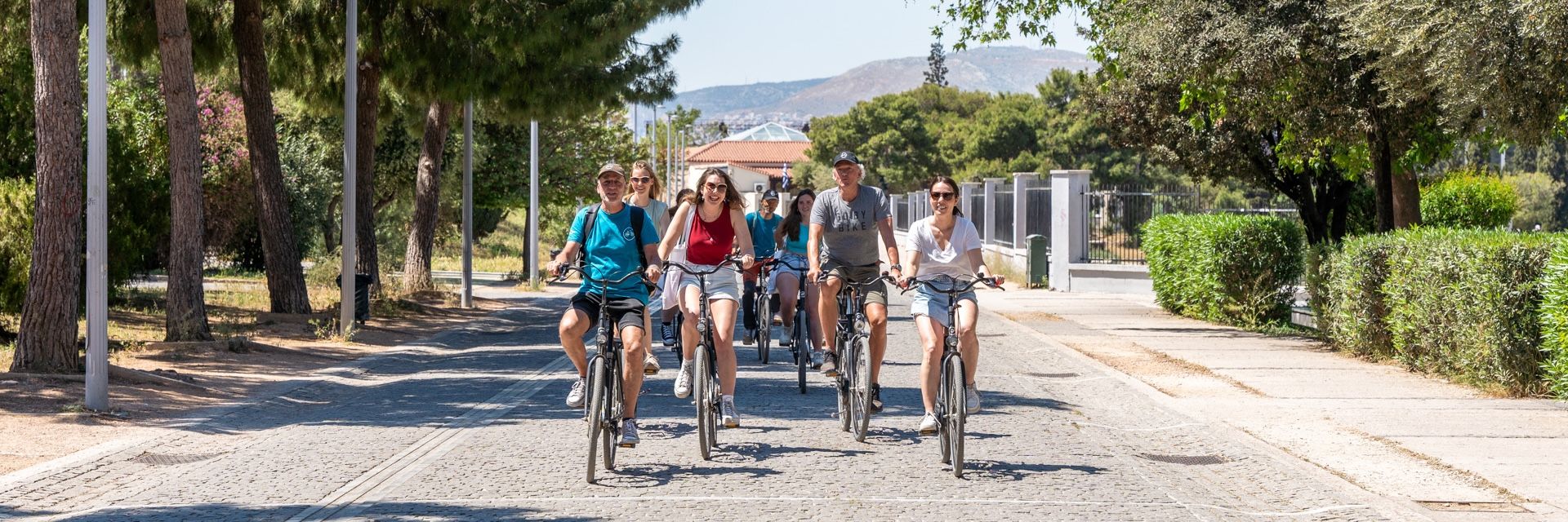 Meet in Athens medewerkers en klanten fietsen door een straat vol met bomen.